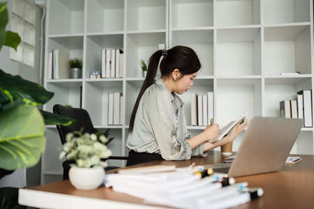 business woman working with laptop while consulting some invoice and document in working space at homeの写真素材