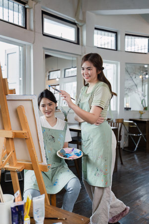 beautiful young woman artist working on painting something on a large canvas
