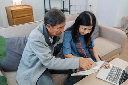 Older couples sit and chat and head over each other relaxed and happy on sofa at home on weekday in comfortableの写真素材