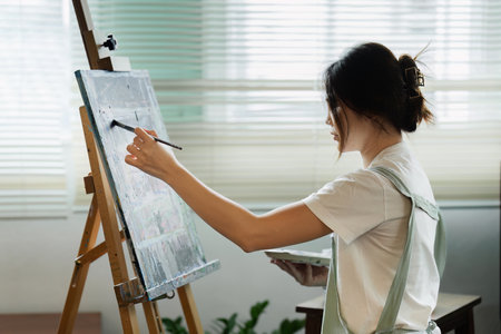 beautiful young woman artist working on painting something on a large canvasの写真素材