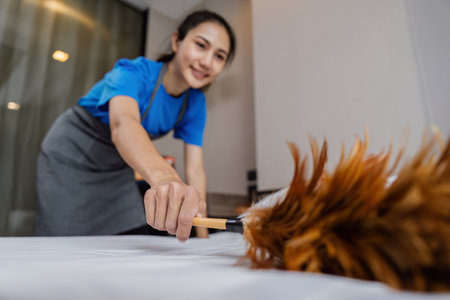 cleaning service woman cleaning dust on bed with feather duster. housekeeping cleaning service...