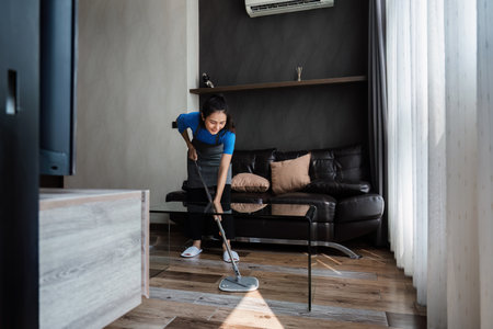 cleaning service housekeeper women swipe floor in living room. House cleaning service concept