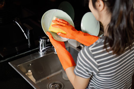housewife cleans the house and washes the dishes at the sink. Cleaning home conceptの写真素材