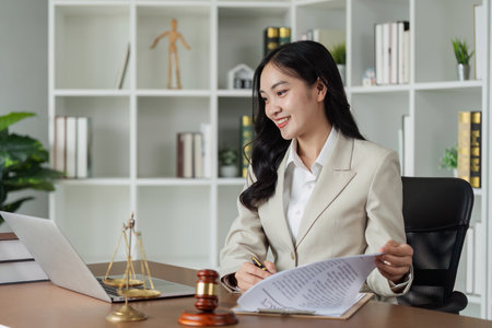 Lawyer sitting at desk and reviewing client document and working on laptopの写真素材