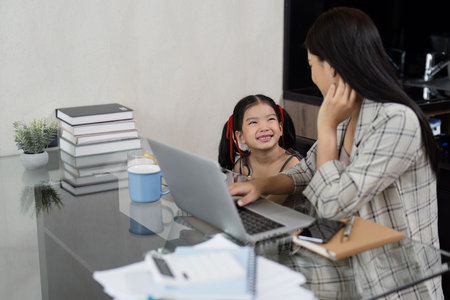 Business woman working at home. working woman working on laptop and take care of her daughter during...