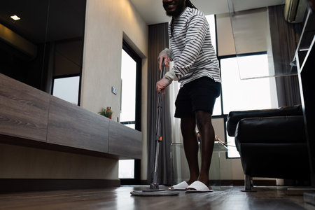 Man Cleaning Modern Home with Mop - Domestic Chores and Housekeeping in Contemporary Living Space - Daily Routine and Home Maintenanceの写真素材