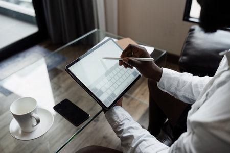 Business man Remote Work with Tablet in Modern Home Office with Coffee Cup and Smartphone on Tableの写真素材
