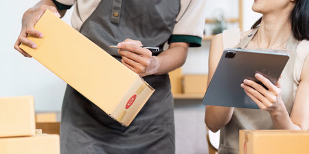 Small Business Owners Managing Inventory and order with Tablet and Boxes in Modern Workspace