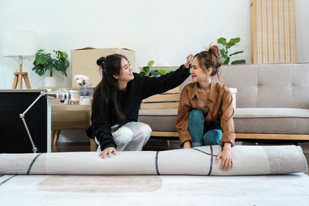 Happy Lesbian Couple Moving into New Home, Unpacking and Decorating Living Room Together, Embracing New Beginningsの写真素材