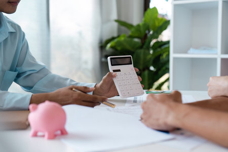 Couple Planning Savings and Banking with Financial Advisor Using Calculator and Documents at Home