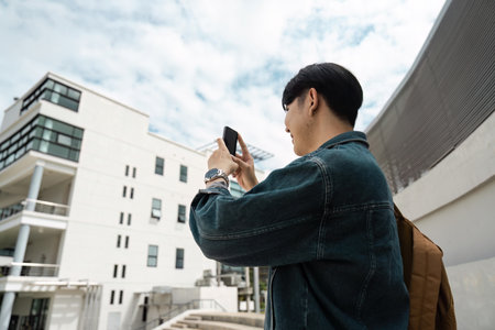 Young Traveler Capturing Modern Architecture on Mobile During Urban Exploration