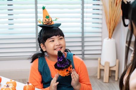 Cute Child in Halloween Costume with Pumpkin Hat and Decorations Indoors Celebrating Halloweenの写真素材