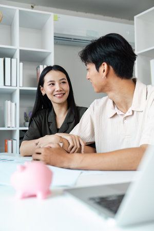 Young Couple Discussing Financial Planning and Savings at Home with Piggy Bank on Tableの写真素材