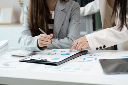 Business Professionals Collaborating on Financial Reports and Data Analysis in Modern Office Settingの写真素材