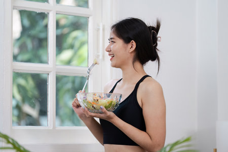 Young Woman Enjoying a Healthy Salad in a Modern Home Setting Promoting Wellness and Healthy Living
