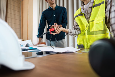 Architect Discussing Construction Plans with Safety Gear and Blueprint on a Table in a Modern Office