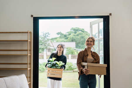 Happy Family Moving into New Home with Boxes and Plants, Excited Women Entering Modern House, Fresh...