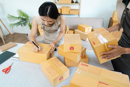 Small Business Owners Preparing Packages for Shipping in a Modern Home Office Environmentの写真素材