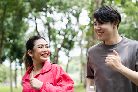 Happy Young Couple Jogging Together in a Park on a Bright Day, Enjoying Outdoor Exercise and Healthy...