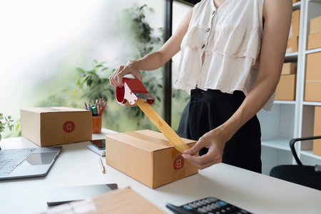 Small Business Owner Packing Order for Online Sales in a Modern Home Officeの写真素材