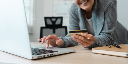 Senior Woman Shopping Online with Credit Card on Laptop at Home, Smiling and Enjoying Convenient...