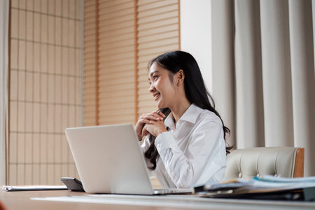 Professional Businesswoman Working at Desk with Laptop in Modern Office Environmentの写真素材