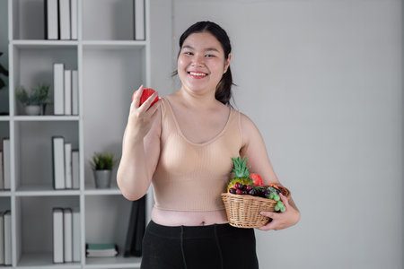 Confident Young Woman Embracing Healthy Lifestyle with Fresh Fruits in Modern Home Settingの写真素材