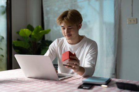 Young Professional Analyzing Real Estate Market Trend on Laptop in Modern Home Office Settingの写真素材