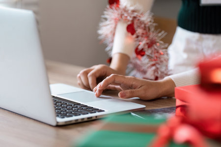 Festive Holiday Shopping Online with Laptop and Christmas Decorations in Cozy Home Settingの写真素材