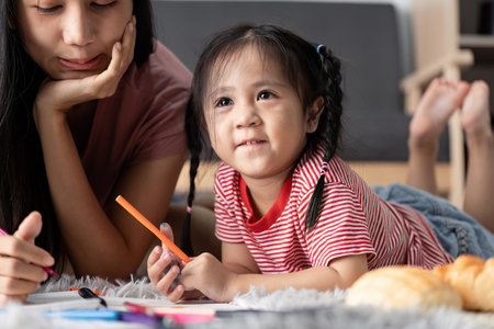 Young Child Engaged in Learning Activities at Home with Parent, Fostering Creativity and Education in a Comfortable Environmentの写真素材