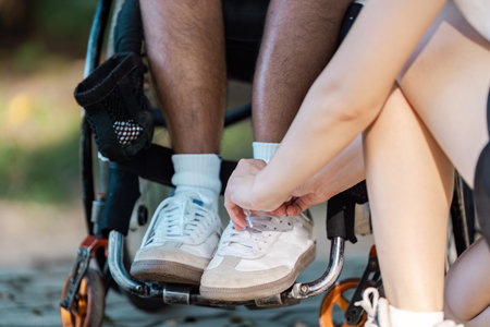 Supportive Interaction with a Disabled Person in a Wheelchair Outdoors on a Sunny Dayの写真素材