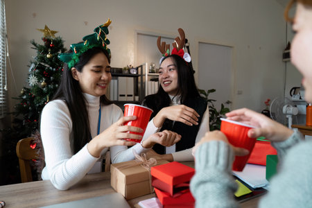 Festive Office Celebration with Colleagues Enjoying Holiday Cheer and Exchanging Gifts in a Decorated Workspaceの写真素材