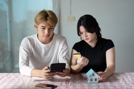 Young Couple Planning Real Estate Investment with Model House and Credit Card at Homeの写真素材