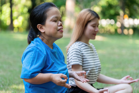 Two Women Meditating Outdoors in a Peaceful Park Setting, Practicing Mindfulness and Relaxation in Nature, Embracing Tranquility and Inner Peaceの写真素材