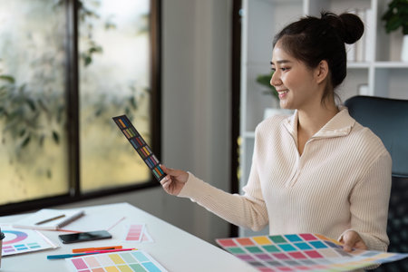 Creative Graphic Designer Working with Color Palettes in Modern Office Environmentの写真素材