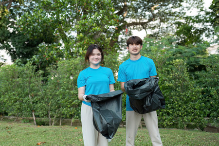 Enthusiastic Volunteers Cleaning Up Park Area with Smiles and Dedication in Community Service Effortの写真素材