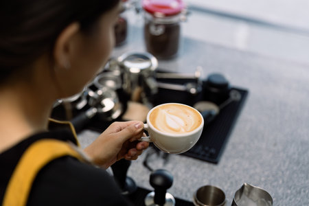 Young Barista Crafting Latte Art in a Modern Startup Coffee Shop Environmentの写真素材