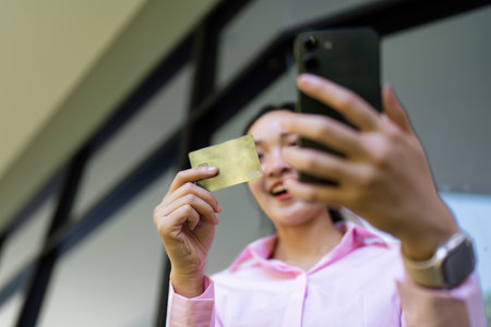 Woman Holding Credit Card and Smartphone for Online Shopping or Mobile Banking in a Modern Setting