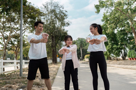Family Enjoying Outdoor Exercise Together on a Sunny Day in a Park Setting with Trees and Clear Blue Skyの写真素材