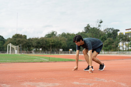 Athlete preparing to sprint sports track action outdoor stadium low angle view focus on determinationの写真素材