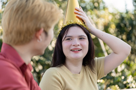 Joyful Outdoor Party Celebration with Friends Wearing Festive Hats and Smiling in a Sunny Garden Settingの写真素材