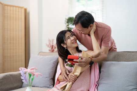 Joyful Senior Couple Celebrating Valentines Day with Flowers and Gifts in a Cozy Home Settingの写真素材