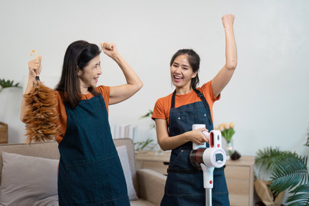 Joyful Housekeepers Engaged in Cleaning Tasks with Modern Equipment in a Cozy Home Environmentの写真素材