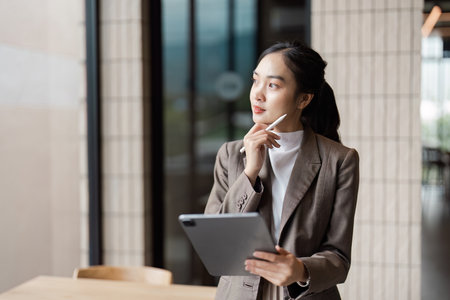 Confident Business Professional Analyzing Data on a Tablet in a Modern Office Environmentの写真素材
