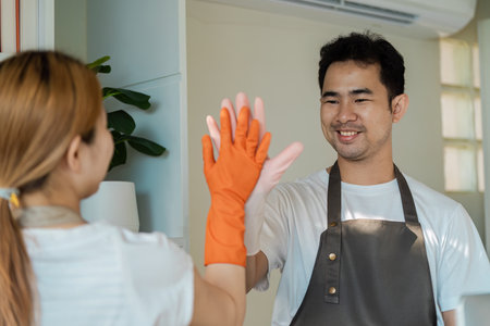 Happy Cleaning Team High-Fiving in Modern Home Environment with Smiling Faces and Positive Energy