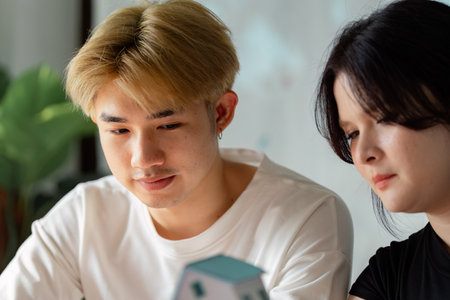 Young couple focused on real estate planning while examining a miniature house model togetherの写真素材