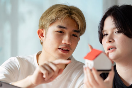 Couple passionately discussing real estate options while examining a miniature house modelの写真素材