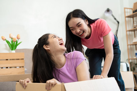 Laughter and joy A lesbian couple sharing a fun moment in a moving boxの写真素材