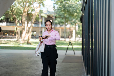 Professional woman checking time during rush hour in an outdoor environment, ready for workの写真素材