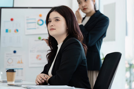 Businesswoman listening thoughtfully during a corporate presentation.の写真素材